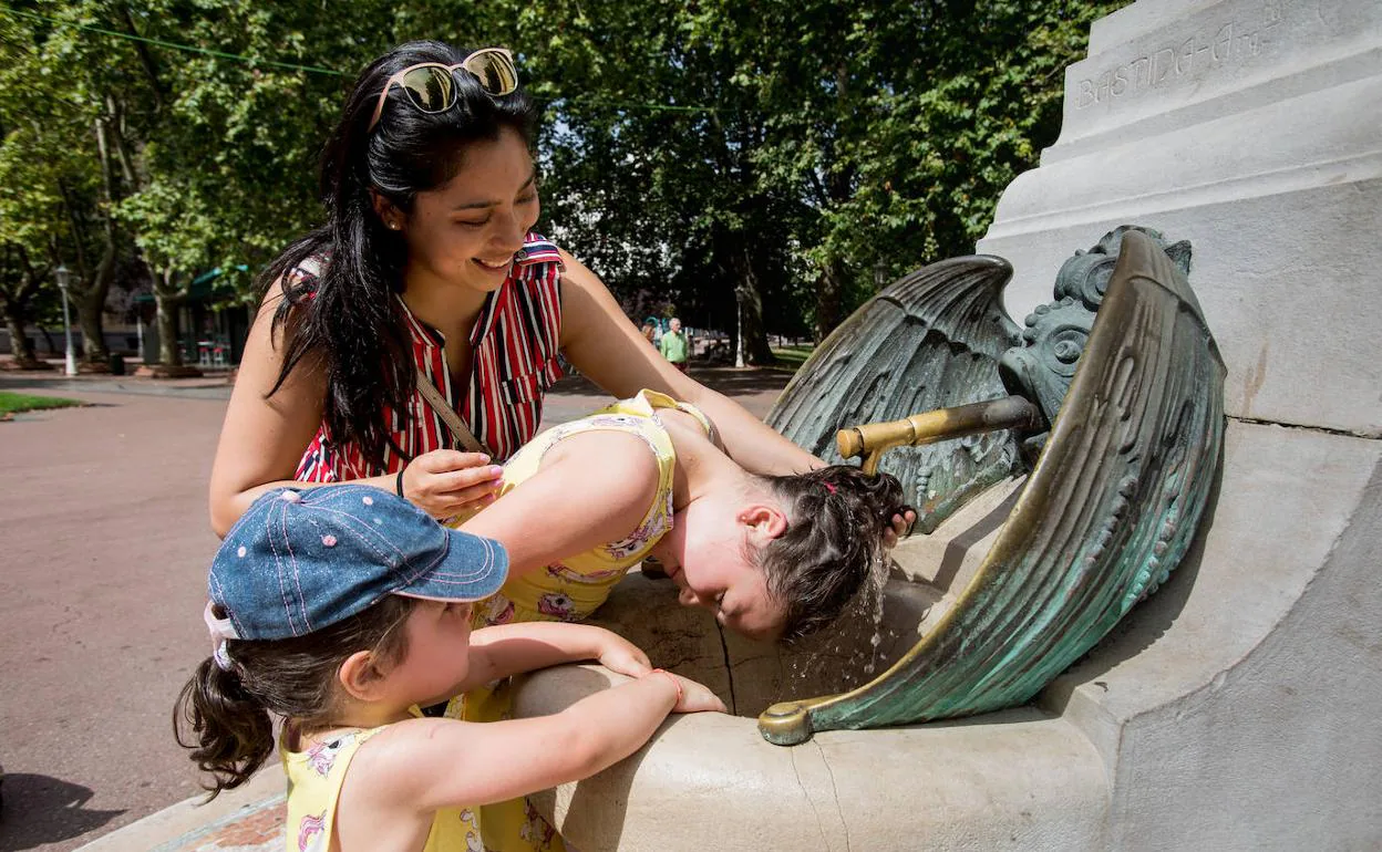 Una mujer refresca a dos niñas en una fuente de Doña Casilda.