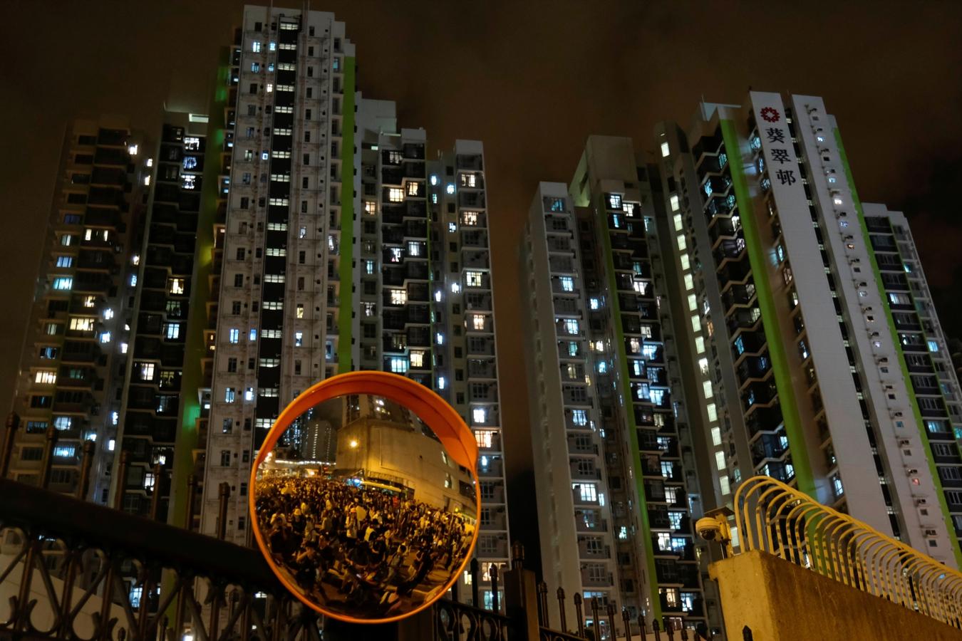 Manifestantes anti-extradición que rodean una estación de policía, donde están detenidos los manifestantes detenidos en los últimos días, son vistos en un espejo en Hong Kong, China