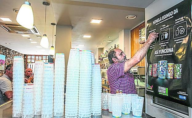 Miguel Ruiz, el del bar Bujanda, hace acopio de vasos reutilizables junto a un panel explicativo sobre su uso durante las fiestas de La Blanca. 