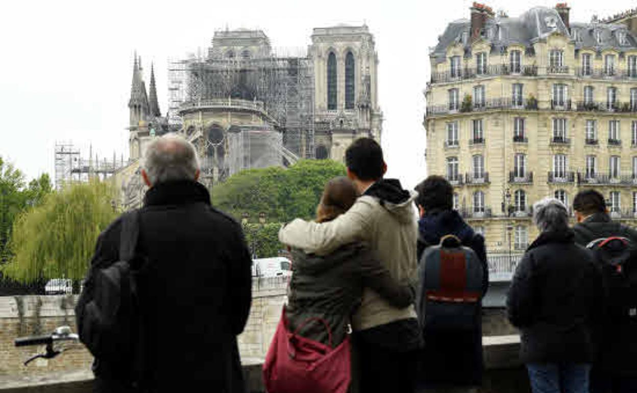 Varias personas observan la reconstrucción de la catedral de Notre - Dame. 