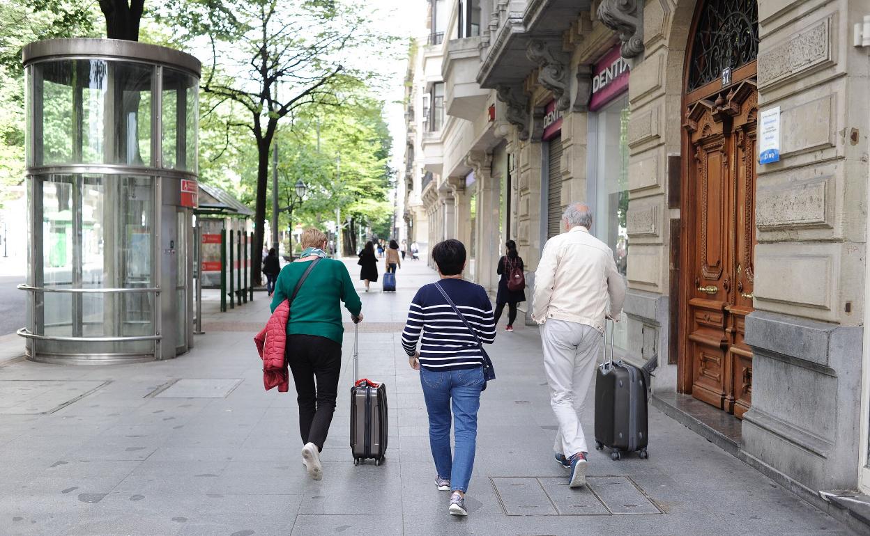 Varios turistas pasean sus maletas por la Gran Vía. 