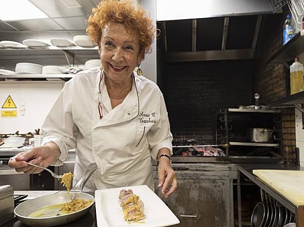 La cocinera del Ganbara añade cebolla pochada al plato.