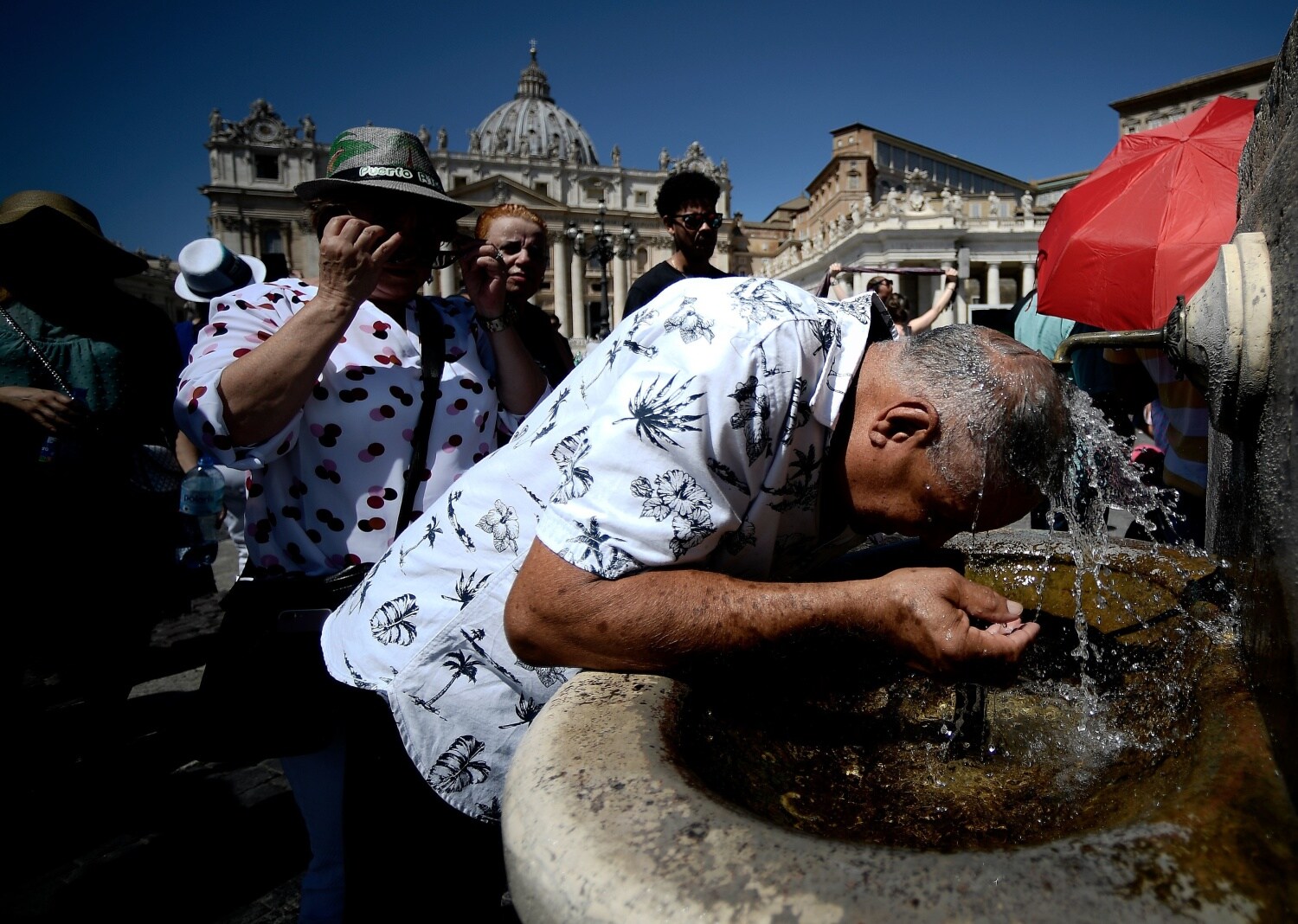 Peregrinos se refrescan en una fuente en la Plaza de San Pedro, en el Vaticano, antes de la oración del Ángelus por el Papa Francisco.