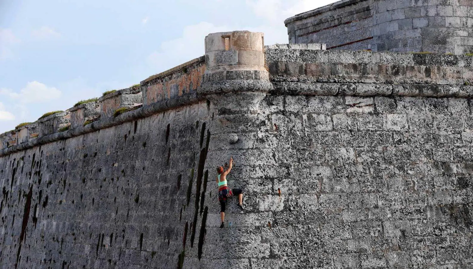 Una mujer escala los muros de la fortaleza del Castillo del Morro en La Habana (Cuba)