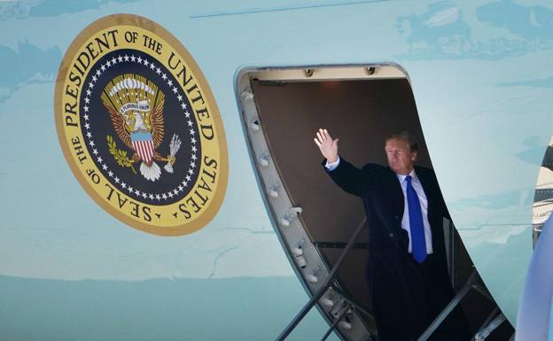 Donal Trump saluda desde la puerta del avión presidencial. 