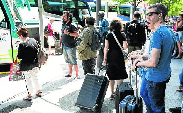 Viajeros esperan su autobús en la estación provisional.