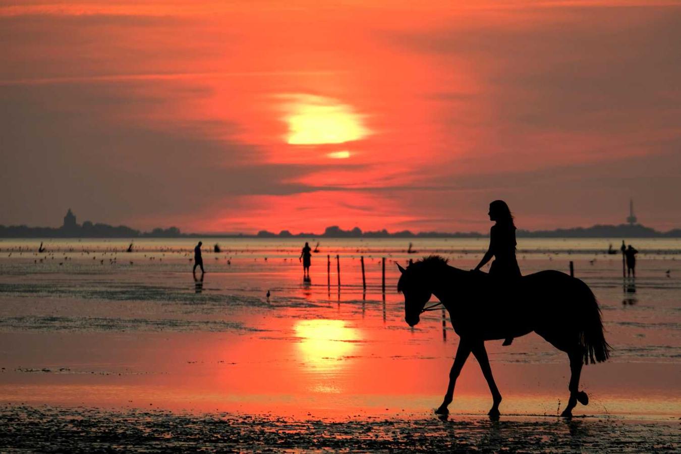 Una mujer monta a caballo en una playa del Mar del Norte en Cuxhaven, Alemania