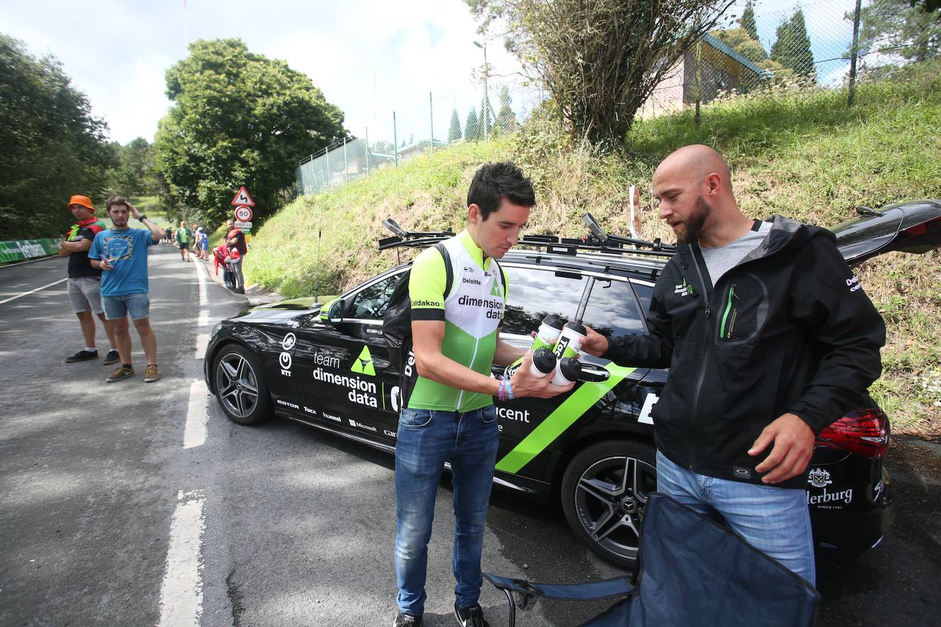 Antón entrega botellines junto a los auxiliares del equipo Dimension Data.