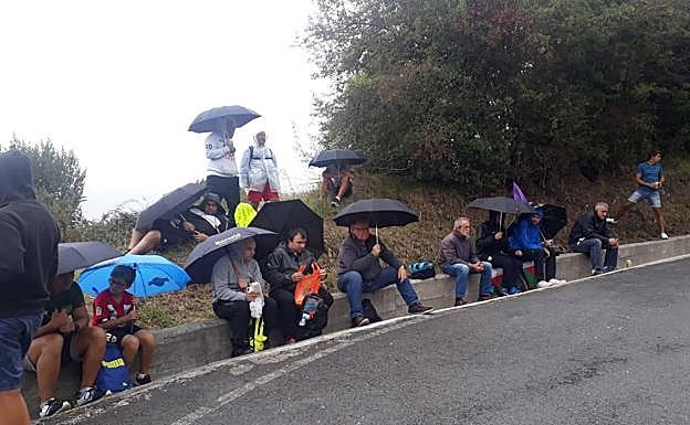 Aficionados esperan bajo su paraguas,
