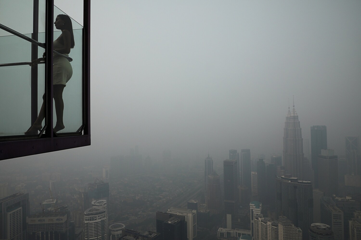 Una turista posa para una foto en la Torre de Kuala Lumpur con el horizonte de la ciudad al fondo envuelto en neblina, en Kuala Lumpur, Malasia