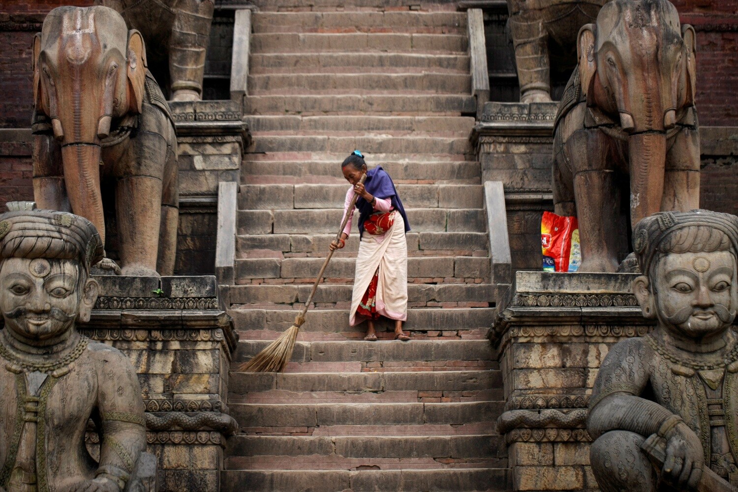 Una mujer barre las escaleras del Templo Nyatapola en Bhaktapur, Nepal