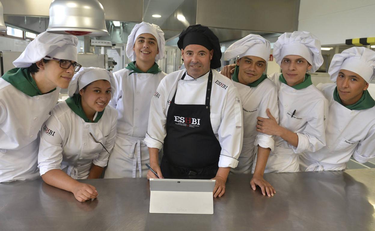 Igor Ozamiz, en el centro y con el mandil negro, rodeado de alumnos en la cocina de la escuela. 