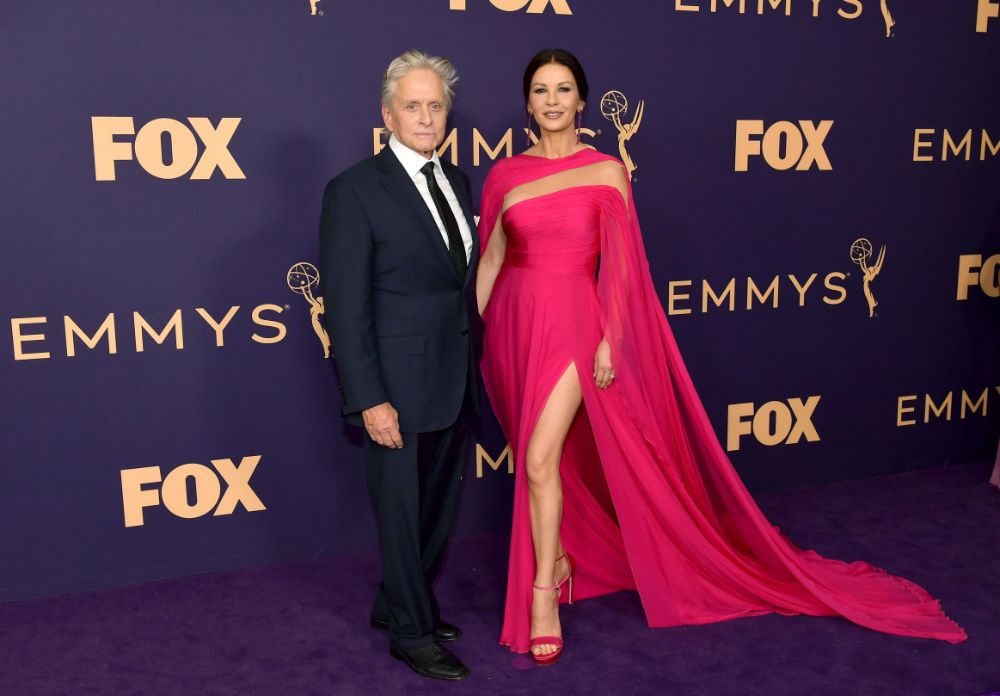 Hollywood se rinde a los pies de Catherine Zeta-Jones una vez más, gracias a un vestido de diva del cine del libanés George Hobeika. Se trata de un diseño de nueva colección que se presentó la anterior semana de la Moda de París. Se trata de un diseño en color fucsia con pronunciada abertura en la falda y escote asimétrico rematado por una teatral capa. A su lado su marido, Michael Douglas, nominado a Mejor Actor Protagonista de comedia, muy elegante con un traje de chaqueta oscuro.