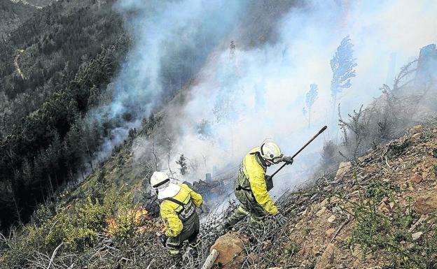 Bomberos apagan el incendio provocado en Muskiz en marzo. El fuego arrasó unas 110 hectáreas y obligó a cortar la autopista.