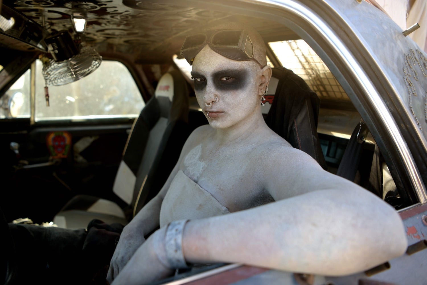 Una mujer en su automóvil durante el festival Wasteland Weekend en el desierto de Mojave en Edwards, California. En 2019, el festival post-apocalíptico más grande del mundo celebra su décimo aniversario con alrededor de 4,000 asistentes. Los organizadores requieren que todos los asistentes al festival estén disfrazados, con la idea de crear un efecto de inmersión completa, haciendo que los asistentes se sientan como si estuvieran dentro de una película al estilo Mad Max durante 5 días. Las actividades incluyen cualquier cantidad de distracciones temáticas del mundo real: bandas en vivo, DJ, cruceros en automóvil, concursos de disfraces, un festival de cine, una competencia de trajes de baño post-apocalípticos, batallas Thunderdome, juegos de rol alegres como un juego de caza de recompensas, talleres de manualidades, peluquería y maquillaje gratis en el salón de belleza patrocinado por el evento, artistas de bomberos, una estación de radio las 24 horas, peleas de gladiadores post-apocalípticas, un campo de tiro con arco, un casino y mucho, mucho más. 