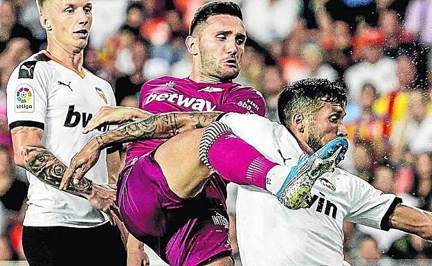 Lucas Pérez intenta un remate ante los valencianistas Wass y Garay en el último partido liguero.