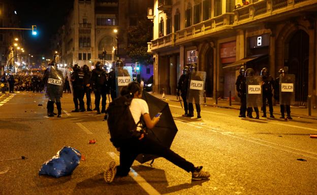 Un joven se esconde tras con un paraguas durante una carga policial en Barcelona. 