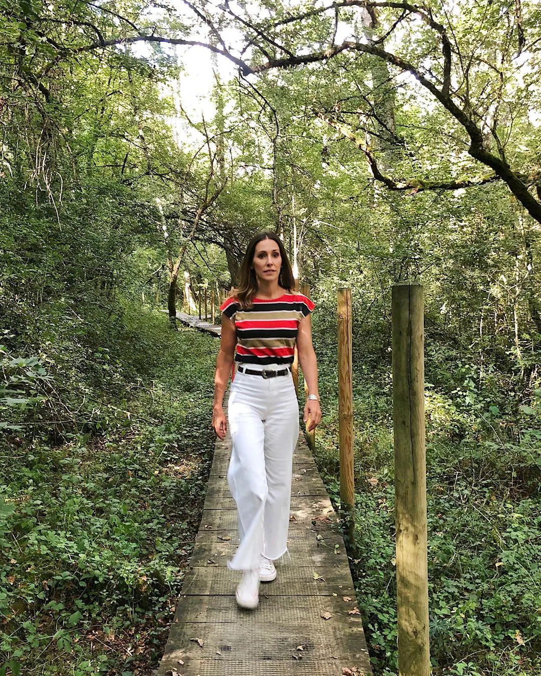 La presentadora Adela Úcar ha elegido un pantalón ancho de Zara en color blanco y con los bajos deshilachados para dar un paseo por el bosque. La camiseta de rayas es de una tienda vintage y las zapatillas son Converse.