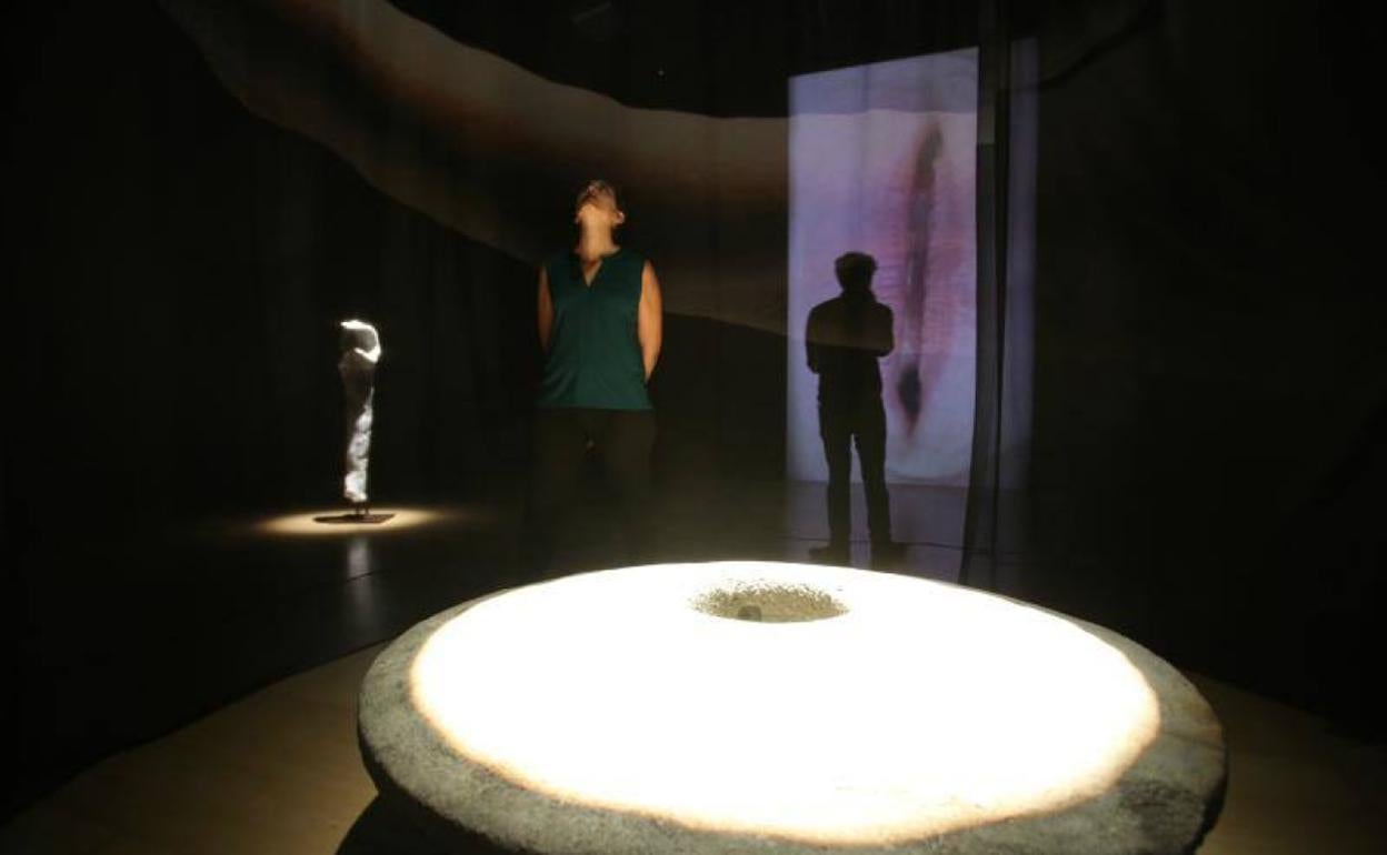 Una de las esculturas de la instalación. Al fondo, una de las dos pantallas de la obra