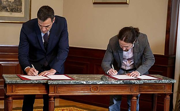 Pedro Sánchez y Pablo Iglesias firmando el acuerdo, este martes.