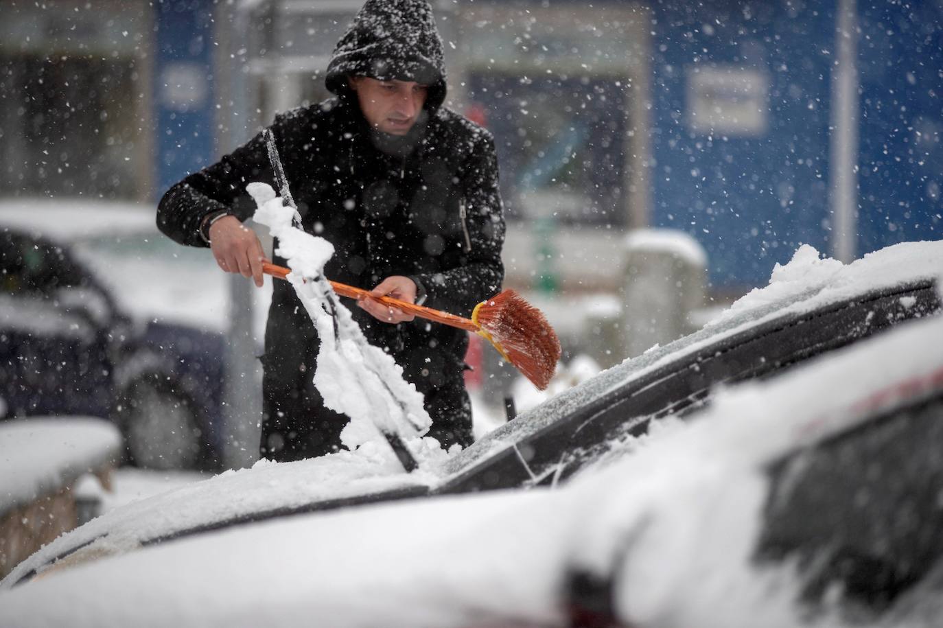 Un hombre quita la nieve con una pala de su coche en un municipio de Lugo. Los colegios de las zonas afectadas por el temporal han suspendido las clases.