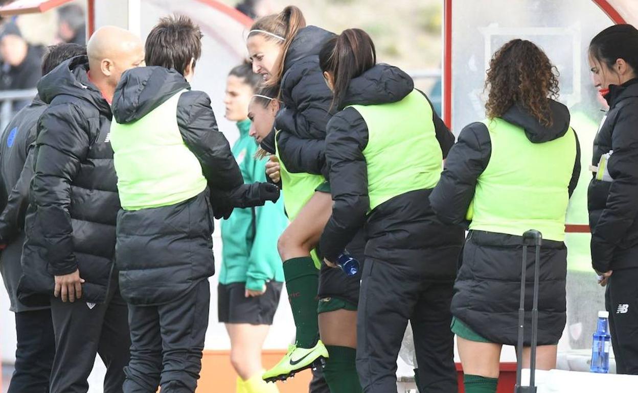 Marta Perea con visibles gestos de dolor yéndose hacia el vestuario ayudada por sus compañeras. 