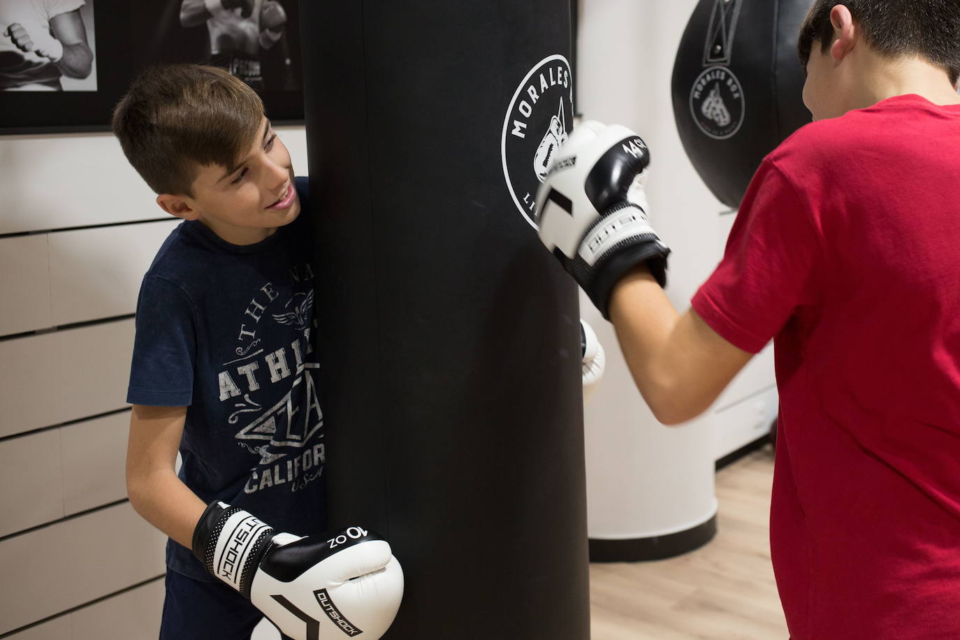 Dos niños realizan ejercicios con el saco de boxeo.