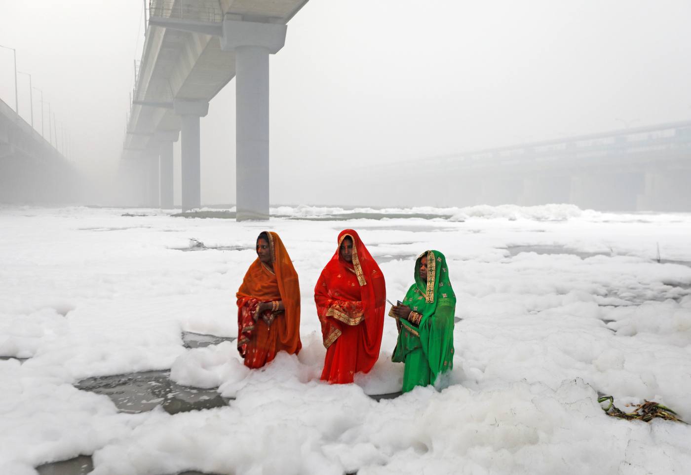 Mujeres indias rezan en medio de las aguas contaminadas y llenas de espuma del río Yamuna durante un festival religioso en Nueva Delhi.