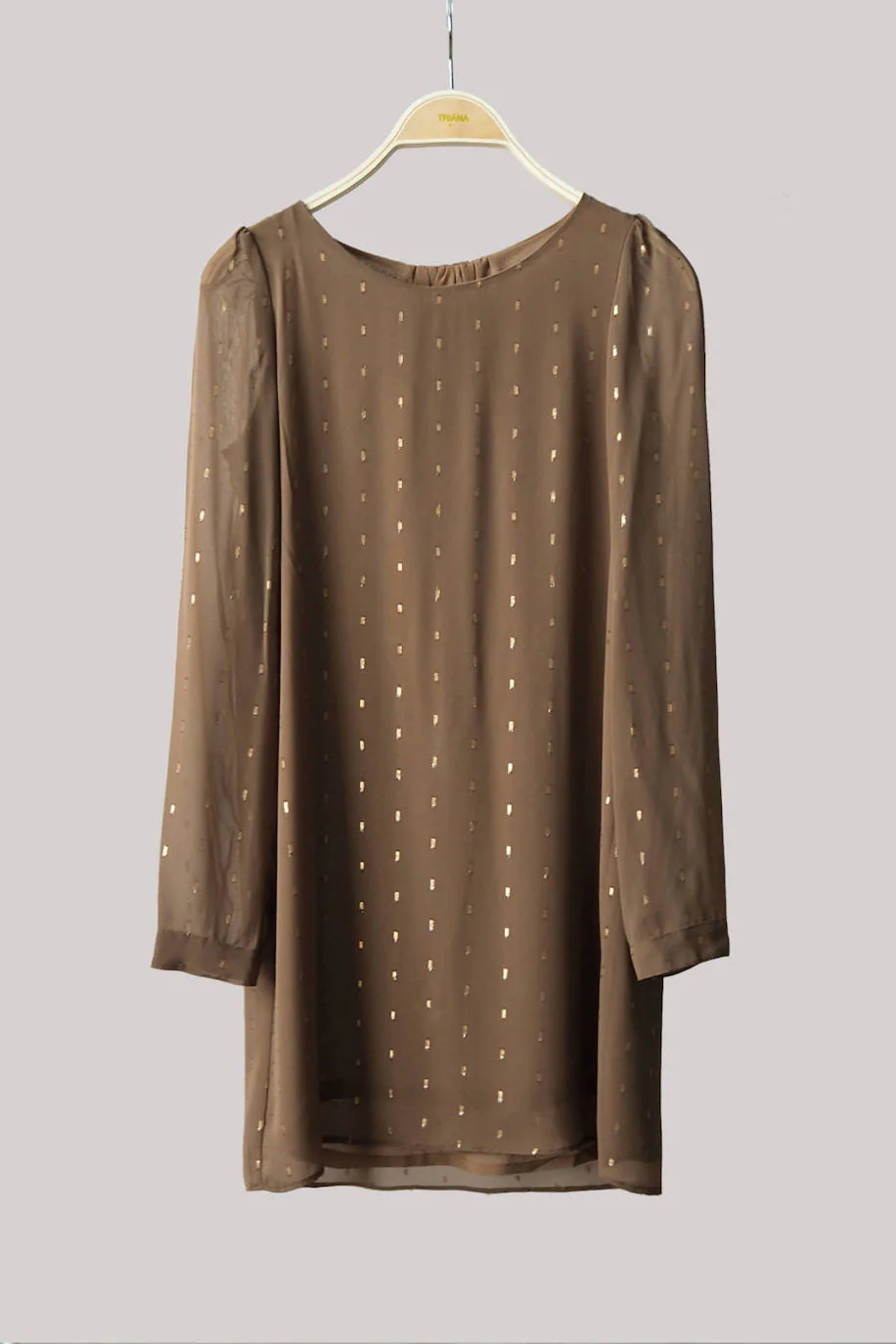 Si te gusta el brillo, aunque no sueles optar por prendas llamativas, siempre puedes lucir un vestido con pequeños detalles dorados como este. Es de la firma bilbaína Triana by C y tiene un precio de 135 euros. 