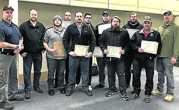 Imagen principal - Arriba, una de las últimas 'promociones' de 'agentes de recuperación de fianzas' que han obtenido el certificado en el 'bootcamp' que Gribbles posee en el Estado de Washington, tras un cursillo de 48 horas. A la izquierda, un alumno encañona a otro durante una clase práctica. A la derecha, una agente del equipo de Gribbles conduce a una mujer esposada, acusada de maltratar a su hijo, a un presidio del condado de Kootenia, en Idaho.