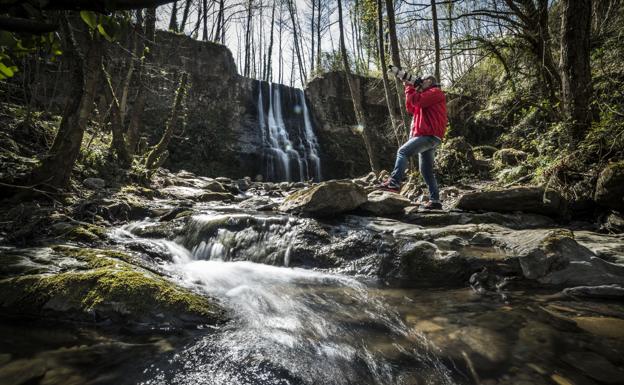 Un fotógrafo se esmera por lograr el mejor ángulo en una cascada en las laderas del Pagasarri.