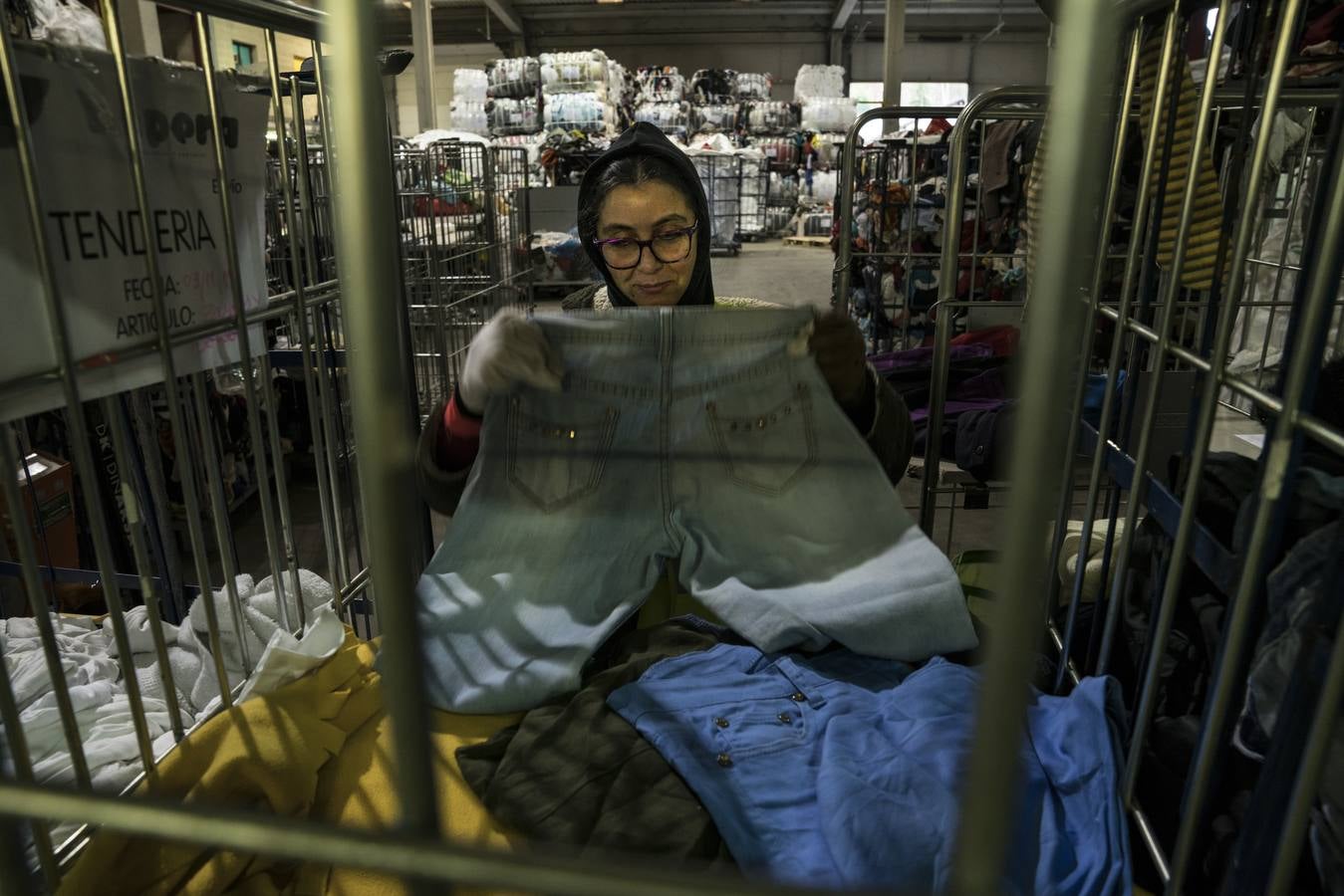Mari Carmen revisa unos pantalones en las jaulas donde se amontona el material que se enviará a las dos tiendas de Koopera en Chile.