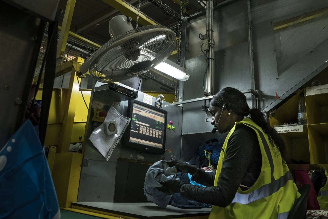 Yacine se sirve de una aplicación por reconocimiento de voz para clasificar según temporada, género o tipo de artículo la avalancha de ropa que pasa de las cintas transportadoras a las tolvas.