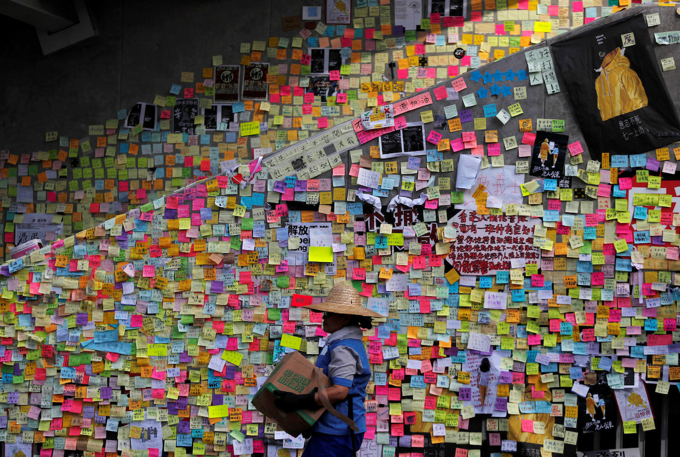 Hong Kong | Un trabajador pasa junto a las notas post-it garabateadas con mensajes dejados por los manifestantes en las paredes del Consejo Legislativo, un día después de que estos irrumpieran en el edificio, 2 de julio de 2019. 