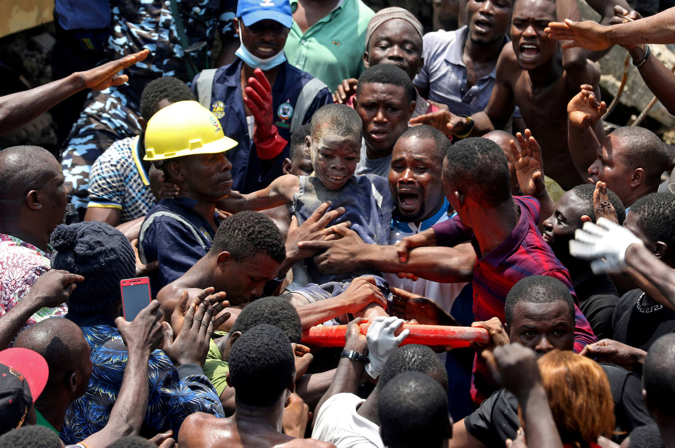 Nigeria | Hombres llevan a Ademola Ayanbola, de nueve años, rescatada tras el derrumbe de un edificio en Lagos, el 13 de marzo de 2019.