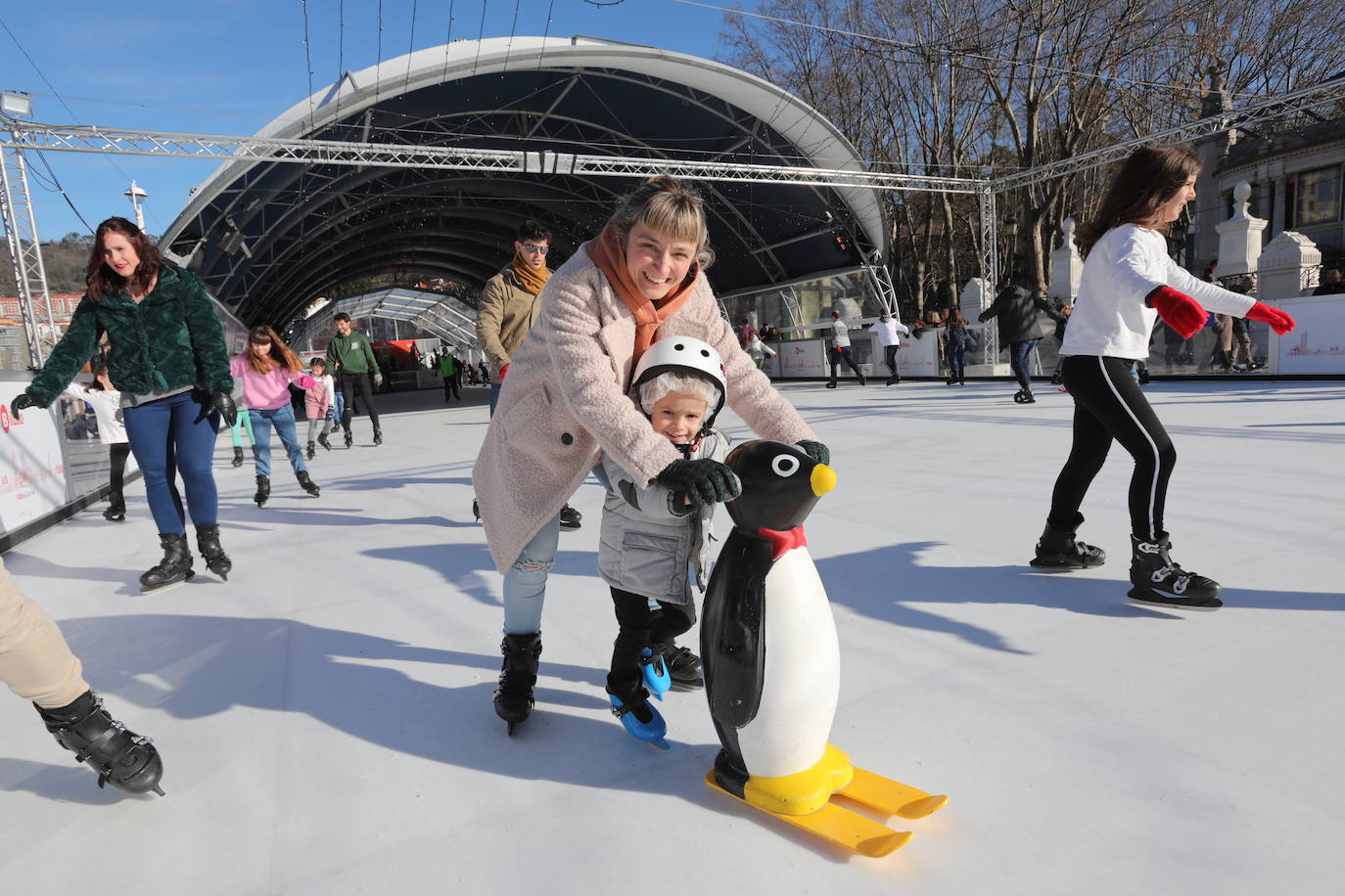 Una niña patina junto a su madre en un pingüino.