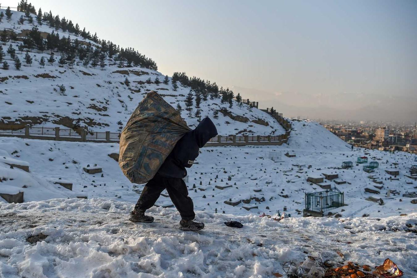 Un joven lleva una bolsa llena de basura por una carretera en Kabul