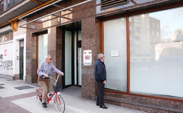 Dos hombres observan la fachada de una sucursal cerrada en Álava.