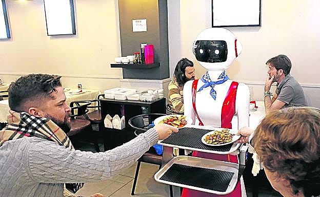 'Nomi' acerca su bandeja con la comanda a dos clientes en el Xing Yuan de Bilbao.