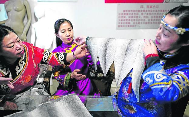 Tradición. Las discípulas Han de You Wenfeng muestran una pieza de cuero en su taller. 