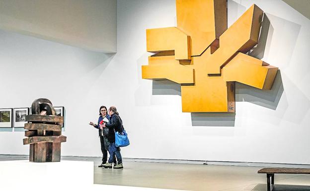 Dos mujeres conversan junto a la pieza de Ibon Aranberri, que suma una radio sintonizable a la incónica escultura de Nestor Basterretxea para el Paralamento Vasco, con piezas de Oteiza y Chillida en primer plano.