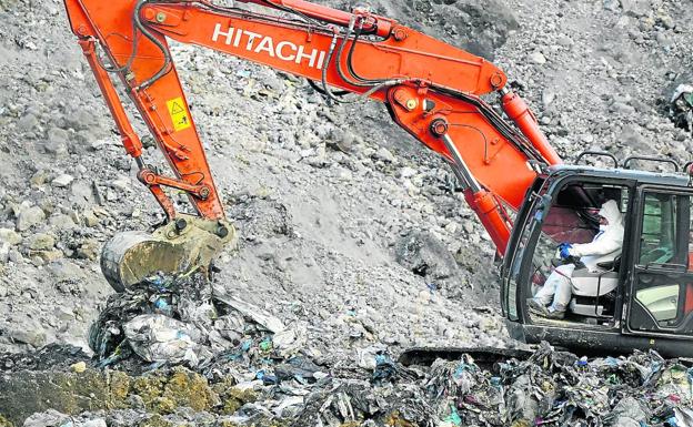 El conductor de una excavadora, pertrechado con ropa de seguridad, trabaja en el desalojo de las rocas.