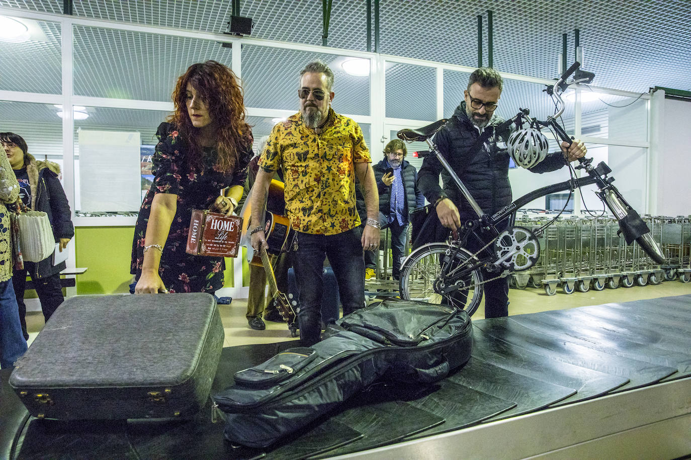 Alicia Mesanza e Ismael Gómez de Segura, que forman el dúo 'Lobo & Carmine', recogen su equipaje. A su lado, el exciclista Álvaro González de Galdeano retira una bicicleta de la cinta.