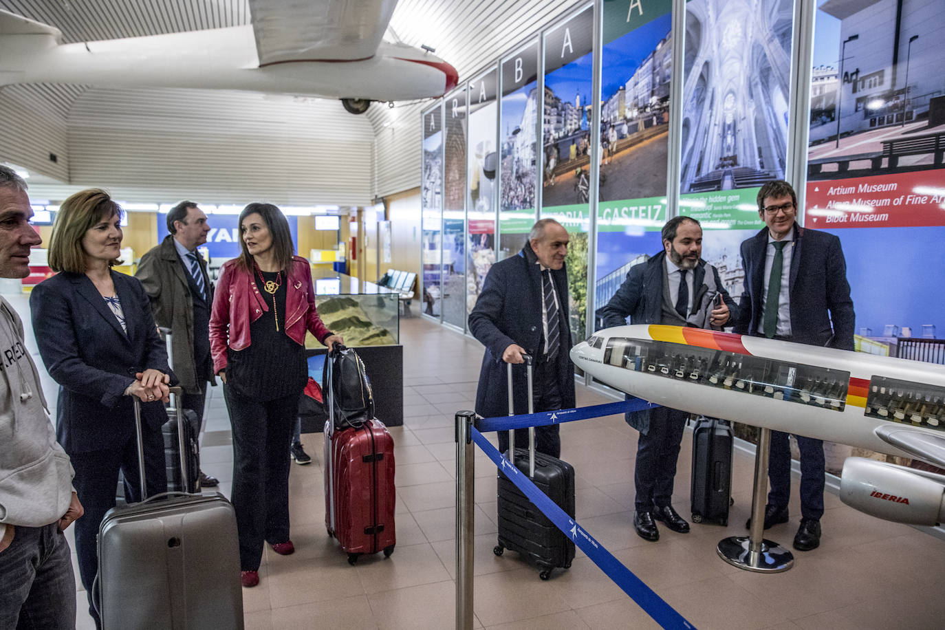 Los protagonistas del reportaje observan la maqueta de una aeronave, situada en la terminal de Foronda, junto a carteles promocionales de Vitoria y Álava.