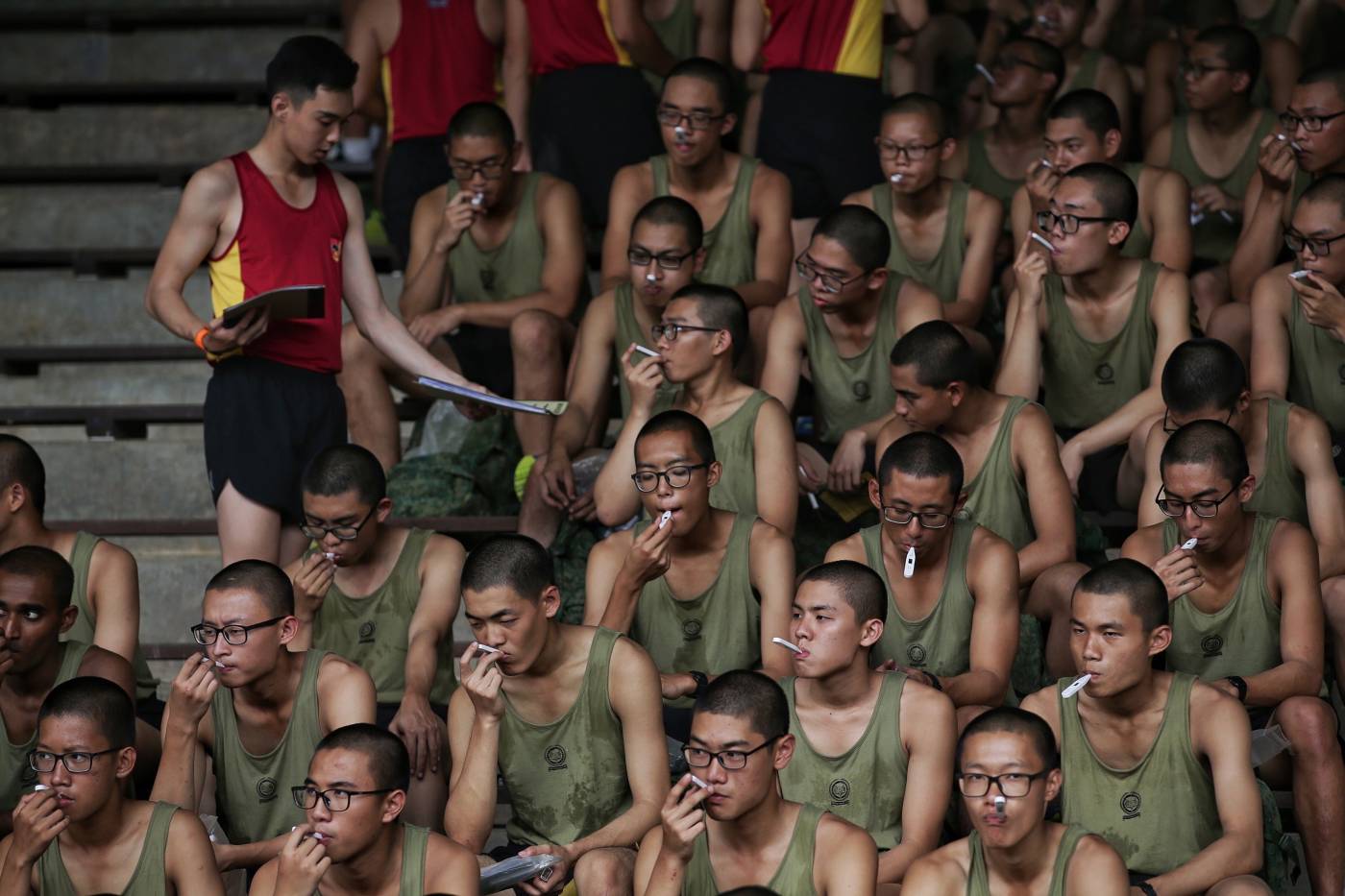 Decenas de reclutas del ejército de Singapur comprueban si tienen fiebre en el Centro de Entrenamiento Militar Básico de la ciudad de Pulau Tekong, en Singapur. Las Fuerzas Armadas de Singapur (FAS) han establecido nuevas medidas de control para prevenir la propagación del coronavirus SARS-CoV-2. 
