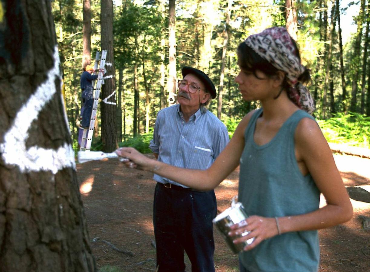 El artista vasco Agustín Ibarrola junto a las pinturas que fueron restauradas en el bosque de Oma por estudiantes de Bellas Artes de la UPV.