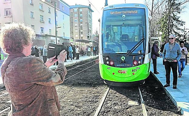 Una mujer toma una foto del tranvía en la parada de Universidad.