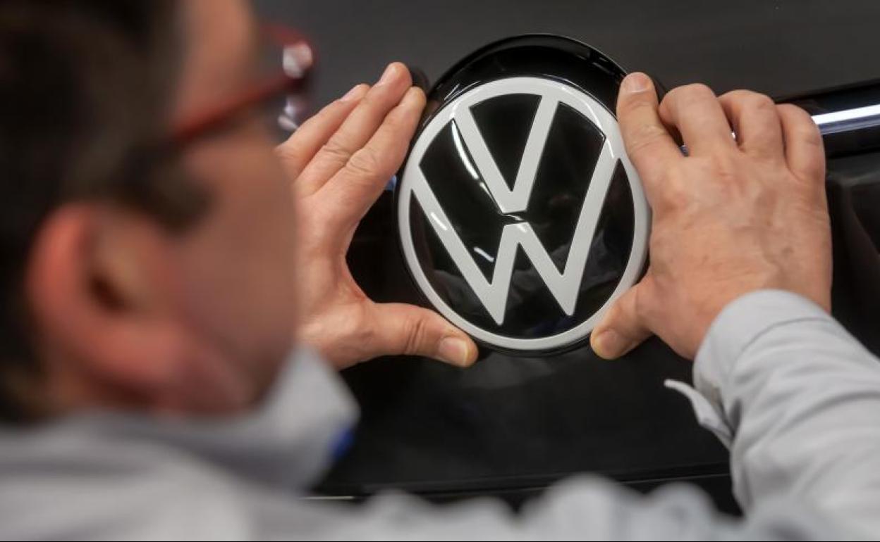 Un empleado de Volkswagen arregla un logo de la firma 