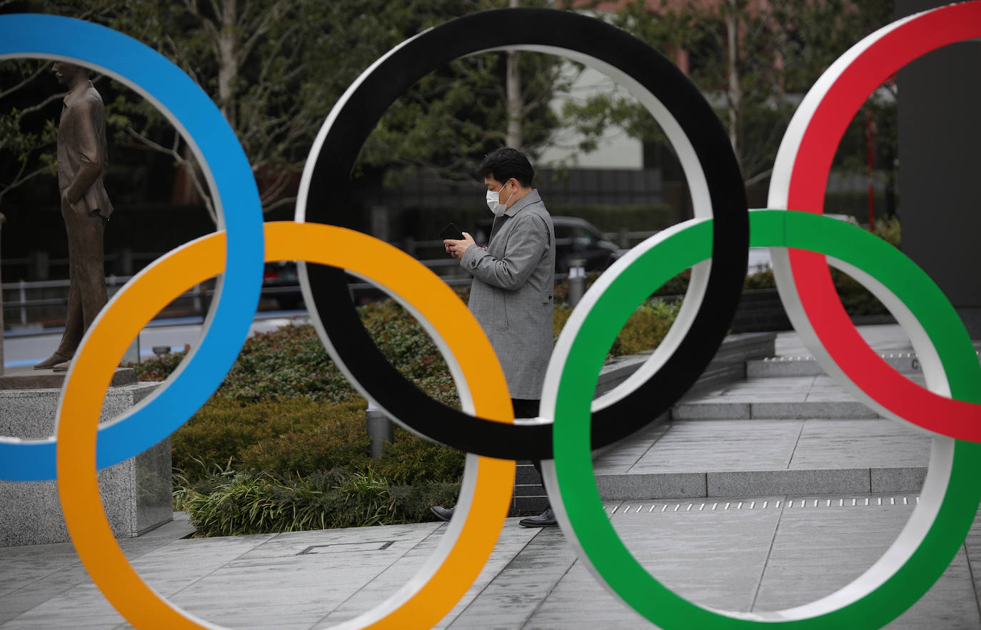 Un hombre que usa una máscara facial protectora consulta su teléfono móvil frente al Museo Olímpico en Tokio.