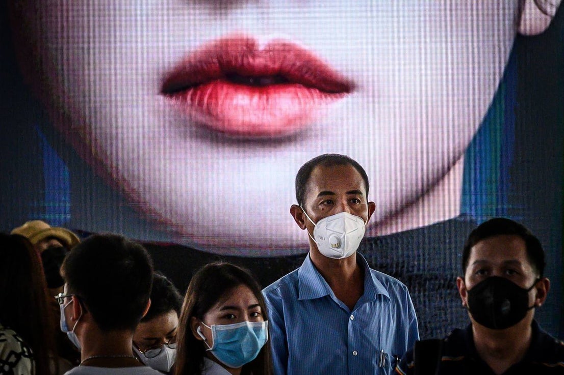 Viandantes con mascarillas caminan en una estación de tren en Bangkok.